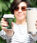 Asian woman smile, hold and show insulated tumbler and squeeze single use paper coffee cup