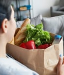 Portrait of female caregiver bringing groceries to senior woman
