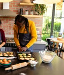 Happy diverse couple in aprons preparing christmas cookies in sunny kitchen. Cooking, baking, christmas, celebration, tradition, togetherness, domestic life and lifestyle, unaltered.