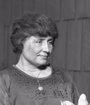 Helen Keller sitting, holding a magnolia flower, circa 1920.
