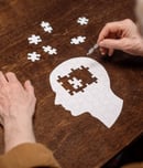 high angle view of senior man collecting jigsaw puzzle as dementia rehab