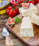 parmesan cheese on wooden cutting board with figues and cherry tomatoes