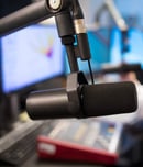 Studio Microphone in Radio Station with Female Host Using Control Panel and Sound Mixer In Background