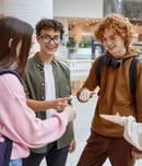 Teenagers friends playing rock-paper-scissors hand game while standing in hall of big shopping mall