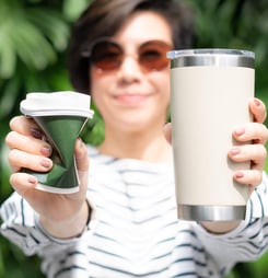 Asian woman smile, hold and show insulated tumbler and squeeze single use paper coffee cup