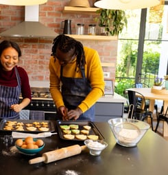 Happy diverse couple in aprons preparing christmas cookies in sunny kitchen. Cooking, baking, christmas, celebration, tradition, togetherness, domestic life and lifestyle, unaltered.