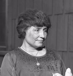 Helen Keller sitting, holding a magnolia flower, circa 1920.