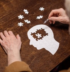 high angle view of senior man collecting jigsaw puzzle as dementia rehab