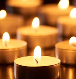 selective focus of burning candles glowing in darkness, panoramic shot