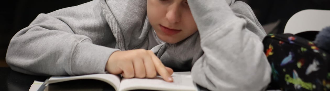 A boy is doing homework, he reading homework, education, teenager boy, learning, back to school.