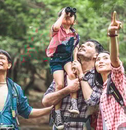 A group of young Asians are planning and looking at maps for camping in the forest.Asian and caucasian are backpackers.Tourism, adventure and summer vacation concept