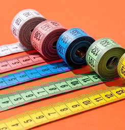 colorful measuring tapes top view on bright red background