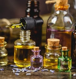 Glass bottles aroma oil, zen stones and dry lavender flowers on wooden table.