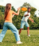 Happy young father with his daughter playing frisbee in the meadow in the park, having fun together on a warm sunny day off.