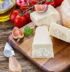 parmesan cheese on wooden cutting board with figues and cherry tomatoes