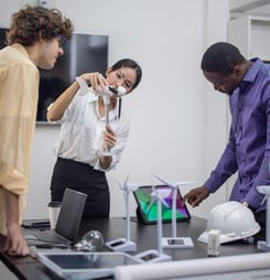 A diverse startup team develop, collaborates on a powerful, lightweight, portable wind turbine prototype, aligning with potential user demand and renewable energy needs to secure investor funding.