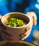 woman seller holds a soup in a disposable eco-dish in her hands.